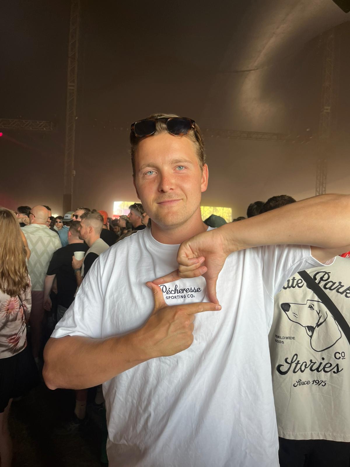 Man pointing to a high quality white t-shirt with text and graphics at an event.