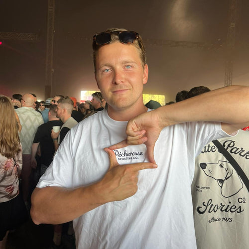 Man pointing to a high quality white t-shirt with text and graphics at an event.